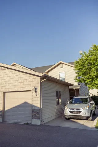 Attached garage with a panel door, stone accent siding, and outdoor wall sconce