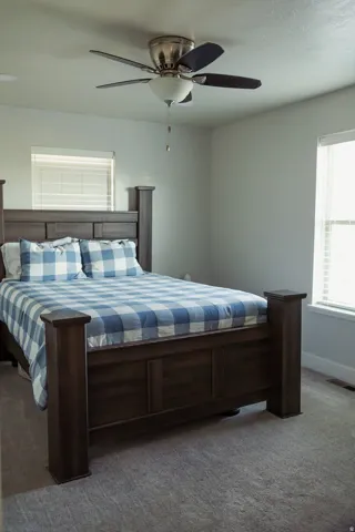Neutral-toned carpeted room featuring a ceiling fan with integrated lighting, recessed lighting, and two windows