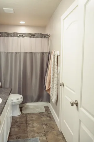 Bathroom featuring a white toilet, tile flooring, and a white vanity with a dark countertop