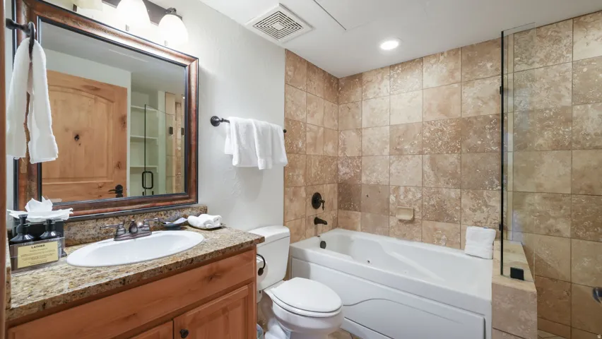 Bathroom featuring a single vanity with stone countertop, drop-in sink, and wood cabinetry