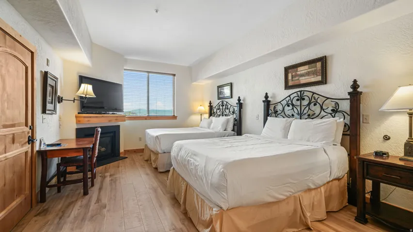 Bright room featuring two beds with ornate metal and wood headboards