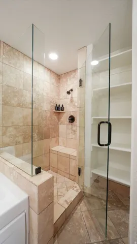 Walk-in shower featuring glass enclosure, built-in bench, recessed lighting, and a dark bronze shower fixture