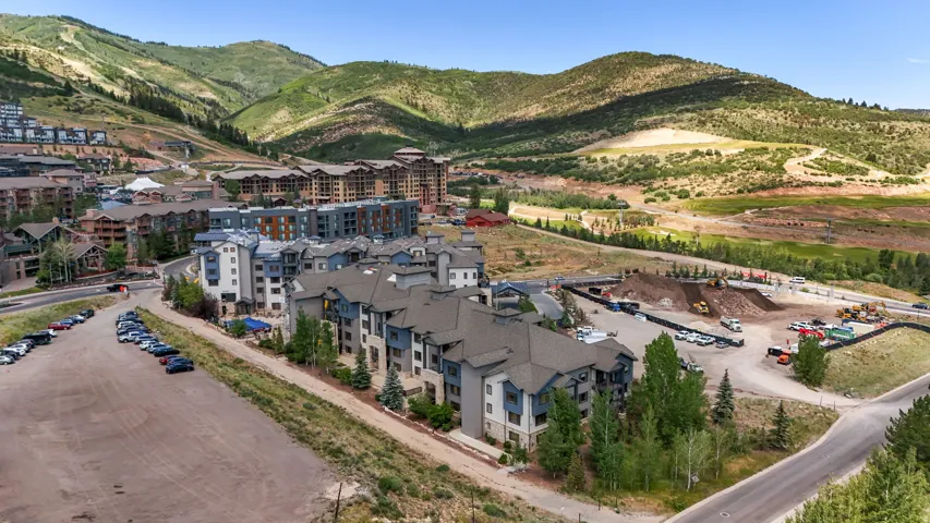 Multi-story residential buildings with varied facades, surrounded by lush green mountains and additional developments