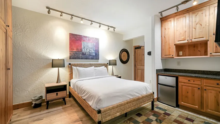 Sleeping area featuring wood-finish flooring, textured wall finishes, and track lighting