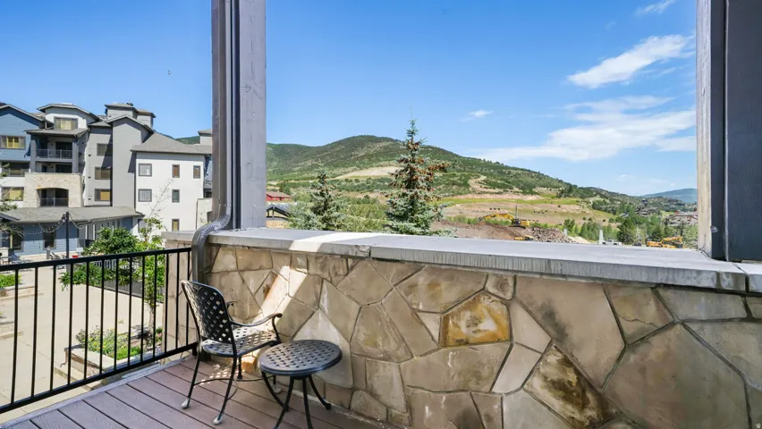 Private balcony with composite decking and black metal railing, featuring a stacked stone partial wall