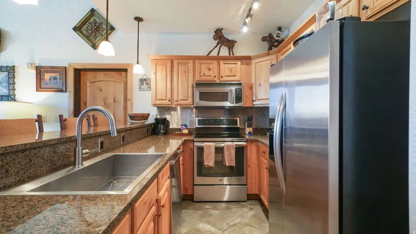 Kitchen featuring a stainless steel undermount sink, gooseneck faucet, light wood cabinetry, and stainless steel appliances