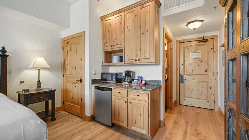 Kitchenette featuring wood-finish cabinetry, granite-style countertop, and stainless steel compact refrigerator