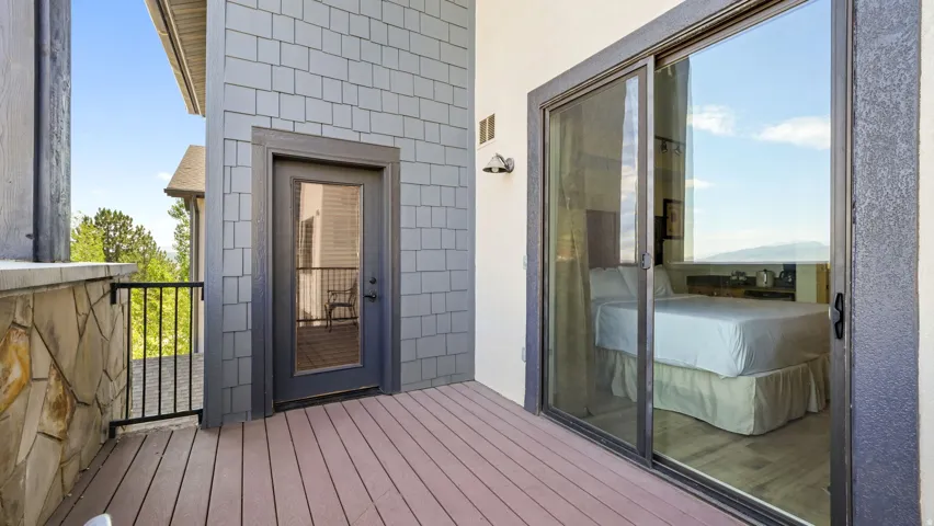 Spacious balcony featuring composite decking, a stone half-wall, and a black metal railing