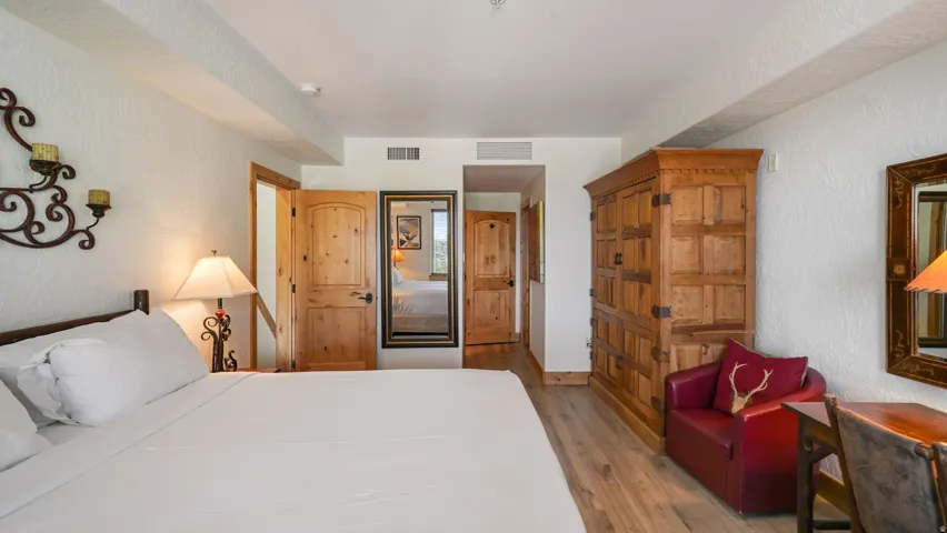 Wood-finish flooring throughout, complemented by a large built-in wood armoire, and natural wood doors with dark hardware