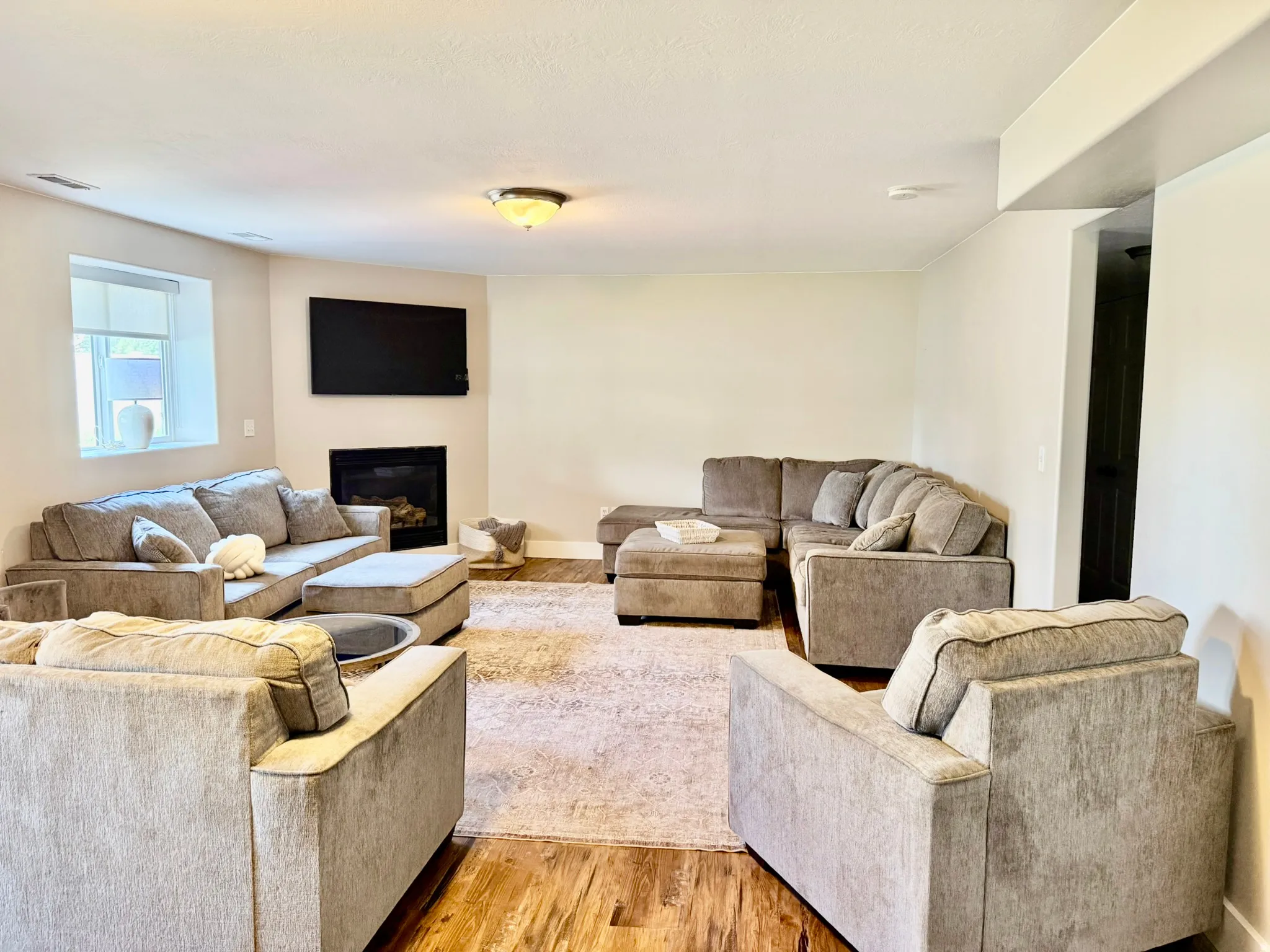 Spacious living area featuring wood-finish flooring, a corner fireplace, and a recessed window