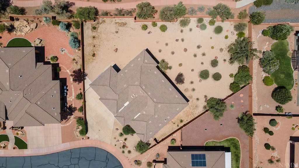 Property featuring a multi-gabled roof, tan stucco exterior, and an expansive xeriscaped yard with desert plantings