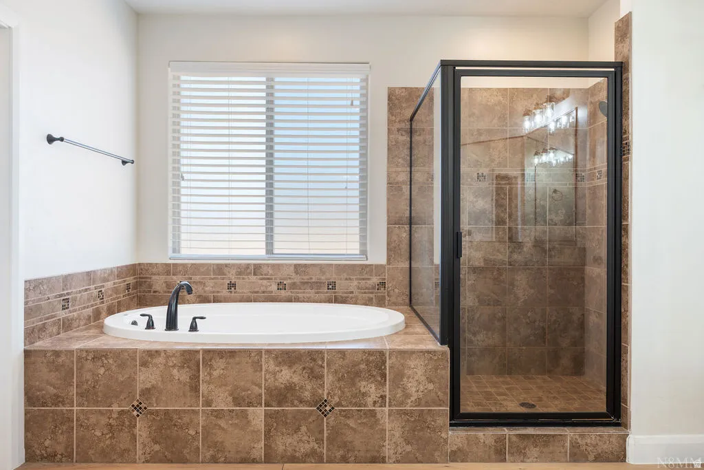 Built-in soaking tub with dark bronze fixtures set in a tiled surround