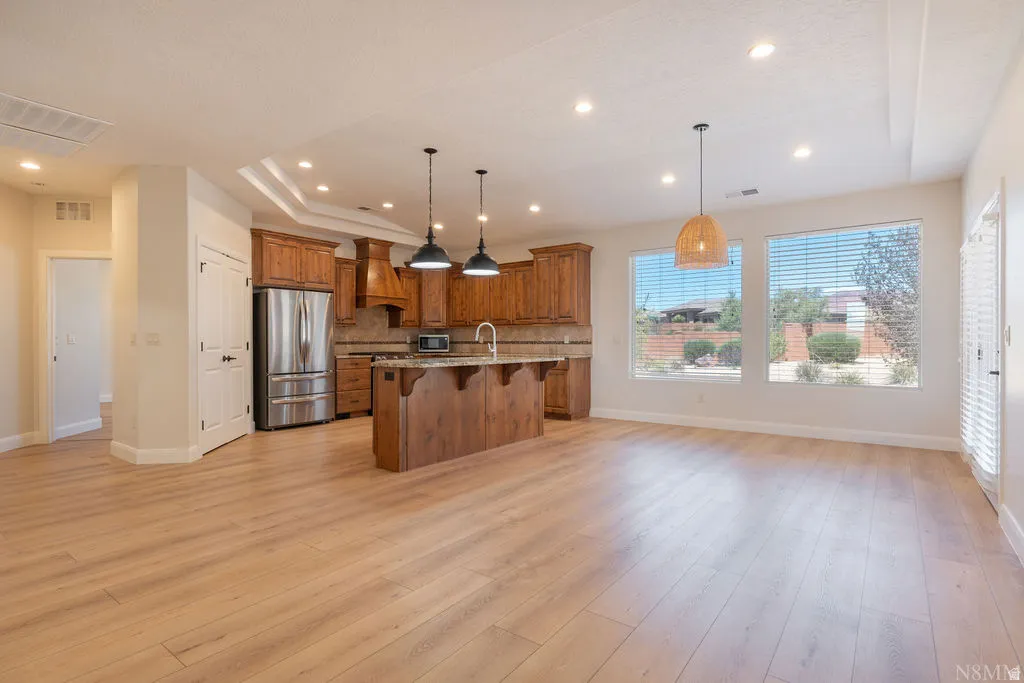 Open-concept living space featuring wood-finish flooring, a kitchen with stainless steel appliances, wood cabinetry, and a central island