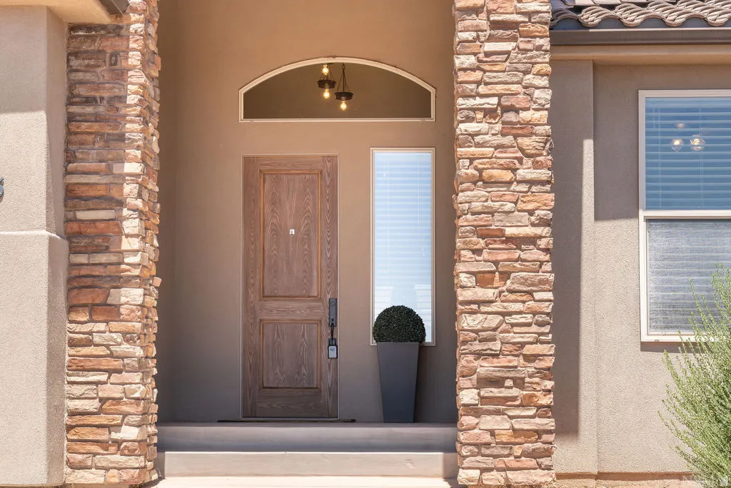 Stone veneer columns frame the inviting entry with a paneled wood-finish door