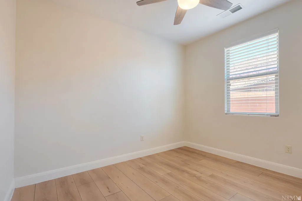 Spacious room featuring wood-finish flooring, white baseboards, and a neutral wall palette