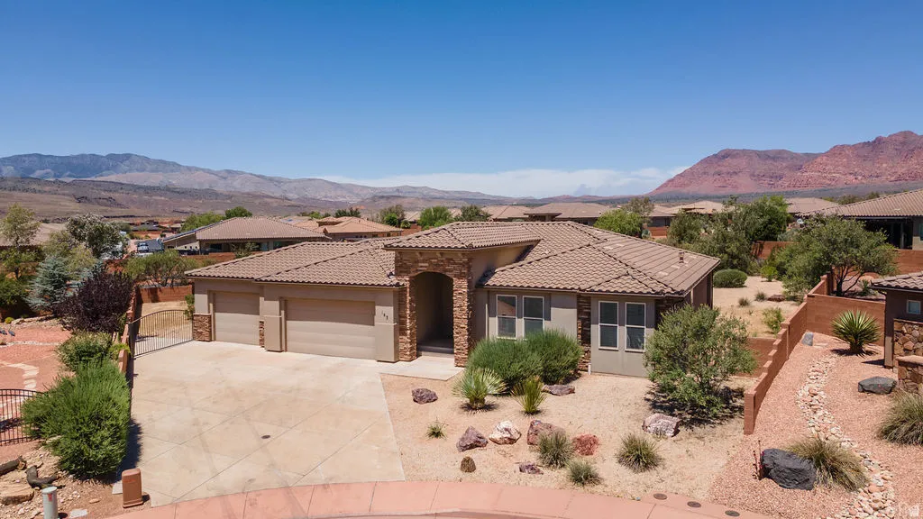Southwestern style residence featuring a tile roof, stone facade accents, and a two-car garage