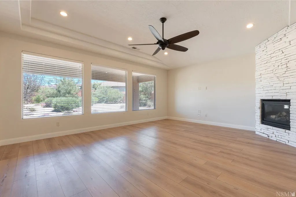Spacious room featuring wood-finish flooring, a contemporary ceiling fan, and recessed lighting