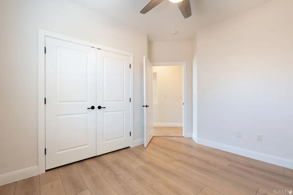 Interior room with wood-finish flooring, white baseboards, and light-toned walls
