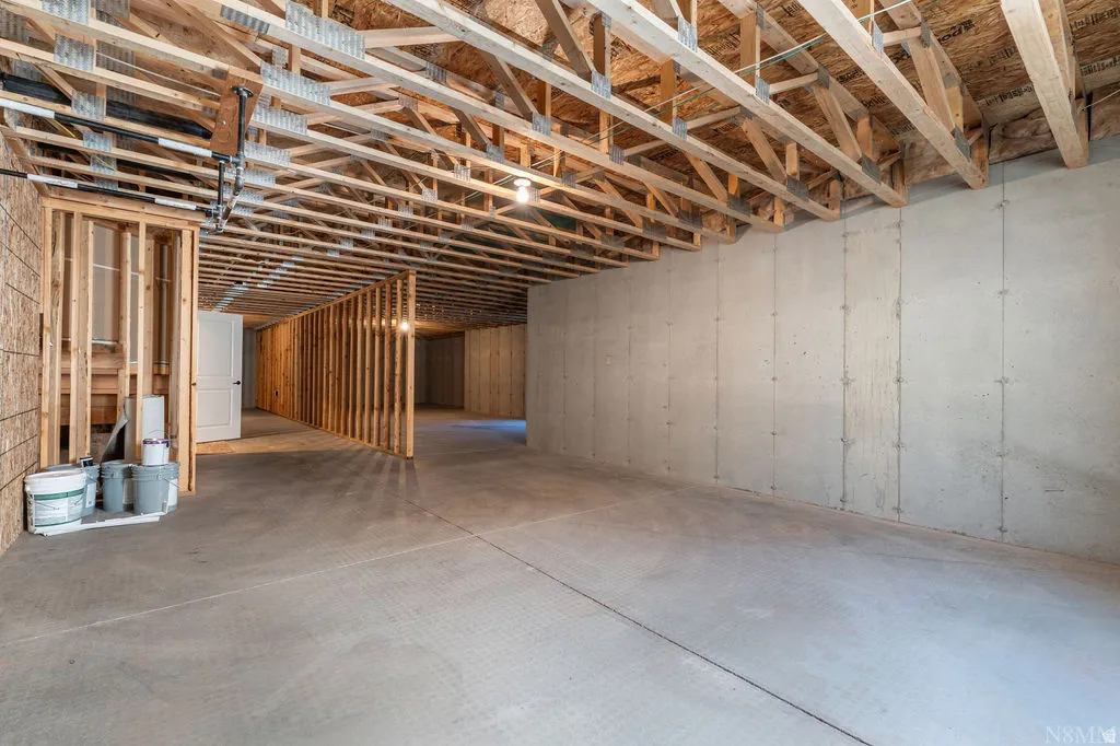 Spacious unfinished basement featuring concrete flooring, exposed ceiling joists, concrete foundation walls, and framed interior walls