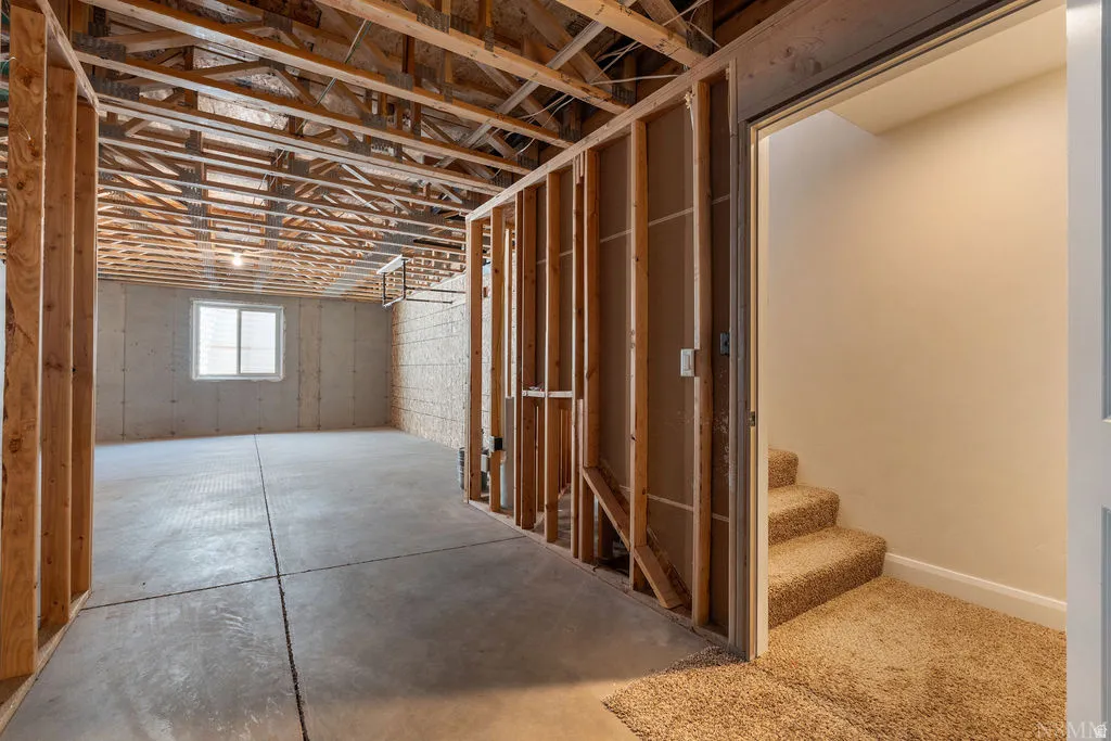 Unfinished basement space featuring exposed wood joists and framing, a concrete floor, and a single window