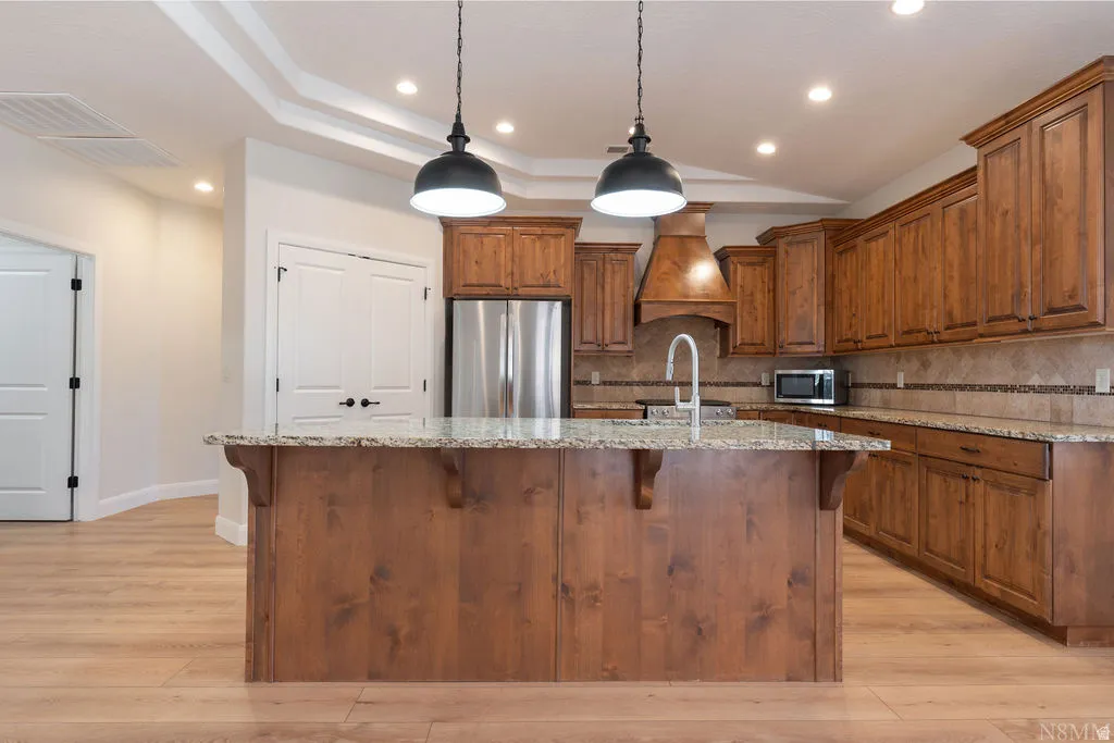 Kitchen island with a granite countertop, undermount sink, and two pendant light fixtures