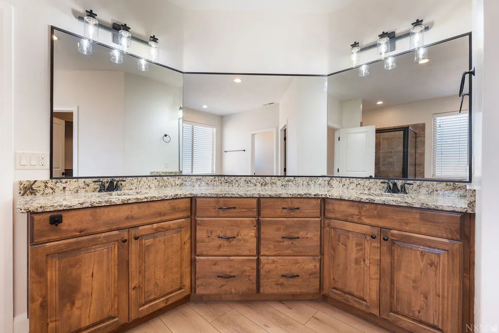 Double vanity with wood-finish cabinetry, speckled countertop, and integrated sinks