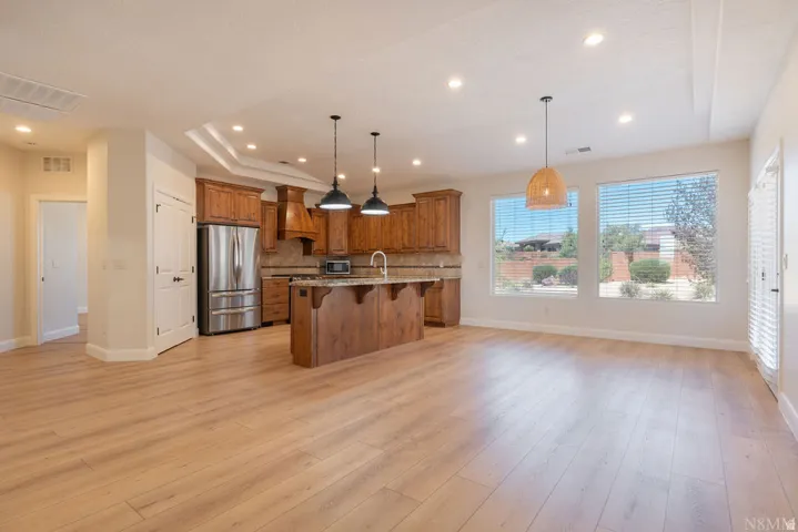 Open-concept living space featuring wood-finish flooring, a kitchen with stainless steel appliances, wood cabinetry, and a central island