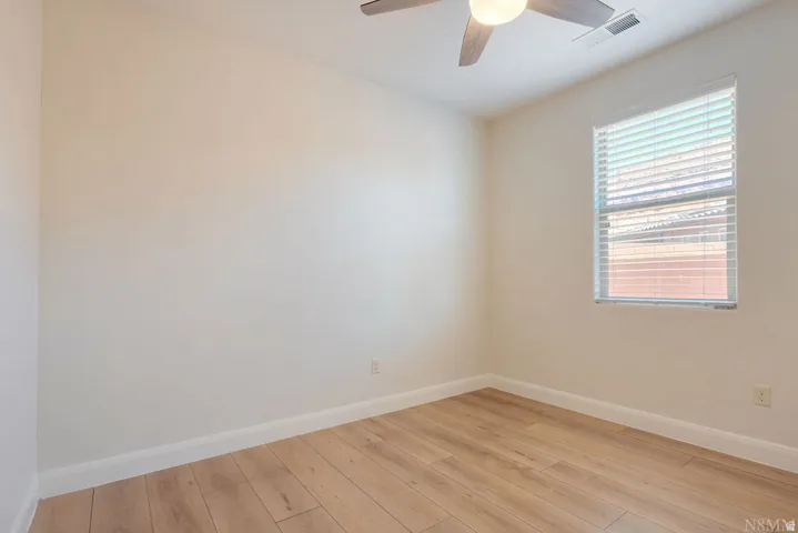 Spacious room featuring wood-finish flooring, white baseboards, and a neutral wall palette