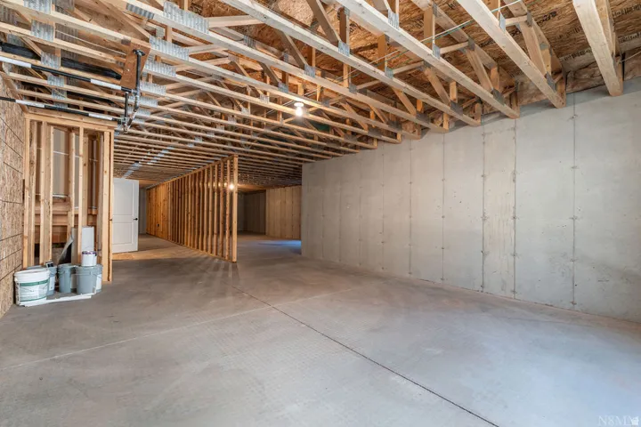 Spacious unfinished basement featuring concrete flooring, exposed ceiling joists, concrete foundation walls, and framed interior walls