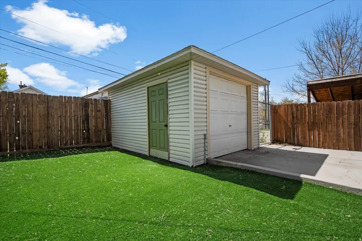 Detached garage featuring white horizontal siding, a light green pedestrian door, and an overhead garage door