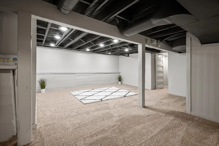 Finished lower level featuring recessed lighting, exposed ceiling joists, neutral carpeting, and painted board and batten paneling
