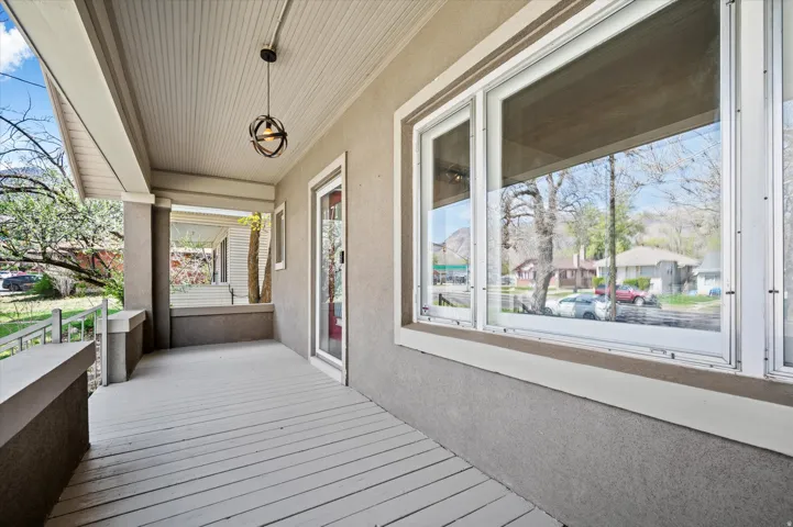 Expansive covered front porch featuring a beadboard ceiling, orb pendant light fixture, and large picture windows