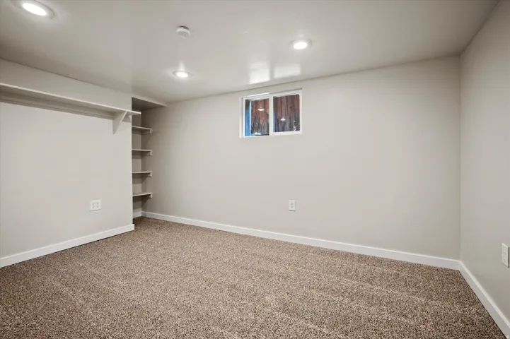 Carpeted room featuring recessed lighting, a window, and built-in shelving
