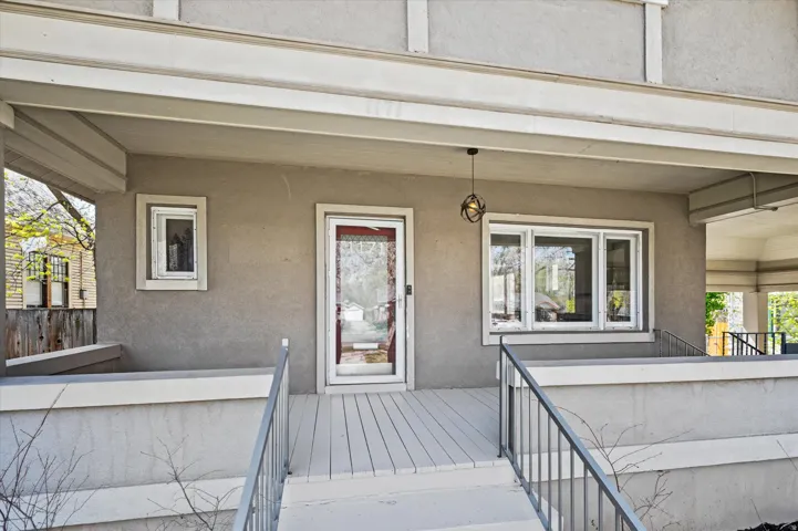 Inviting porch with a gray stucco exterior, white trim accents, and a slatted porch floor