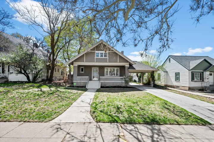 Craftsman-style home featuring a covered entry, gabled roofline, front porch steps, an extended driveway, and mature landscaping