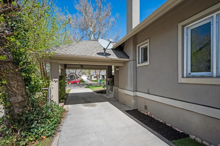 Covered carport entry with a shingle roof and stucco exterior