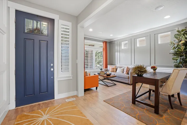 Entryway featuring a paneled navy blue door with a transom window and a white louvered sidelight