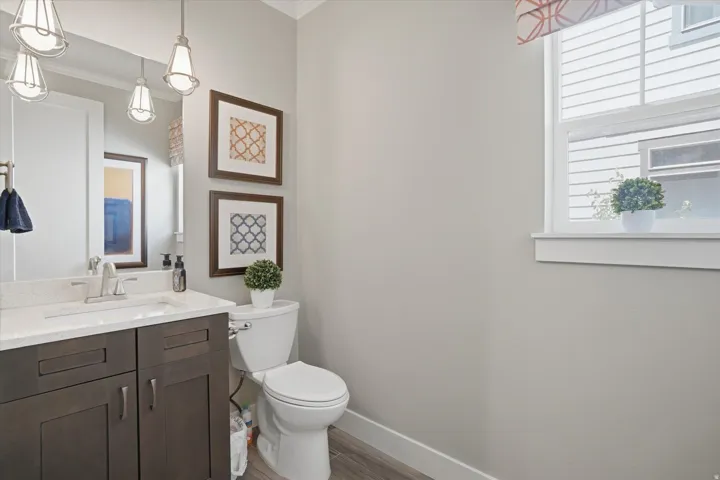 Bathroom featuring a dark wood-finish vanity with a white countertop and undermount sink, brushed nickel faucet, and three pendant light fixtures