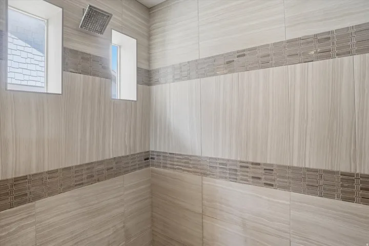 Tiled shower enclosure featuring a rain shower head, two recessed windows, and decorative accent bands