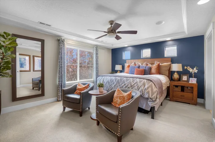 Spacious carpeted room featuring a tray ceiling with recessed lighting and a ceiling fan