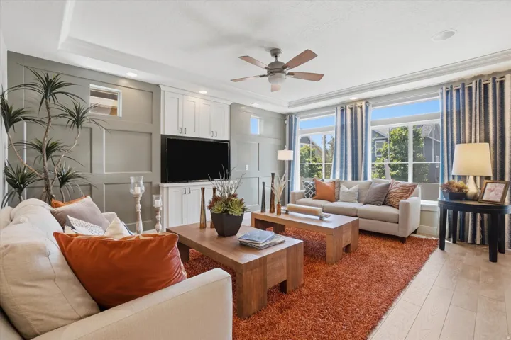 Living area featuring a full wall of board and batten paneling, custom built-in entertainment center, coffered ceiling, and light wood-finish flooring