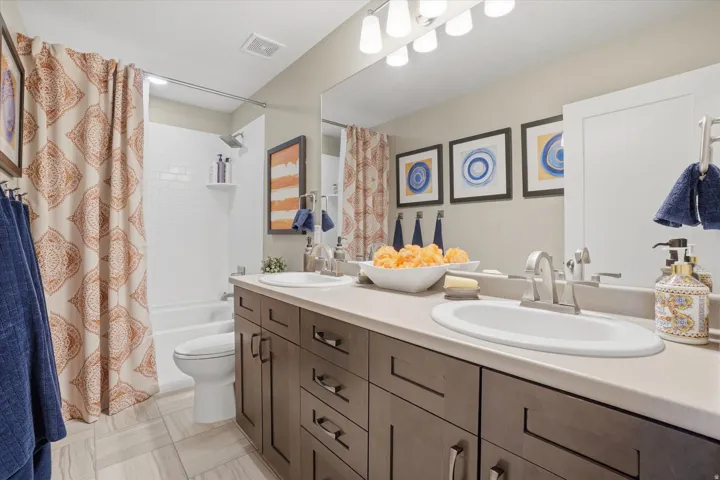 Bathroom featuring a dual vanity with a light-toned countertop, wood-finish cabinetry, and brushed nickel fixtures