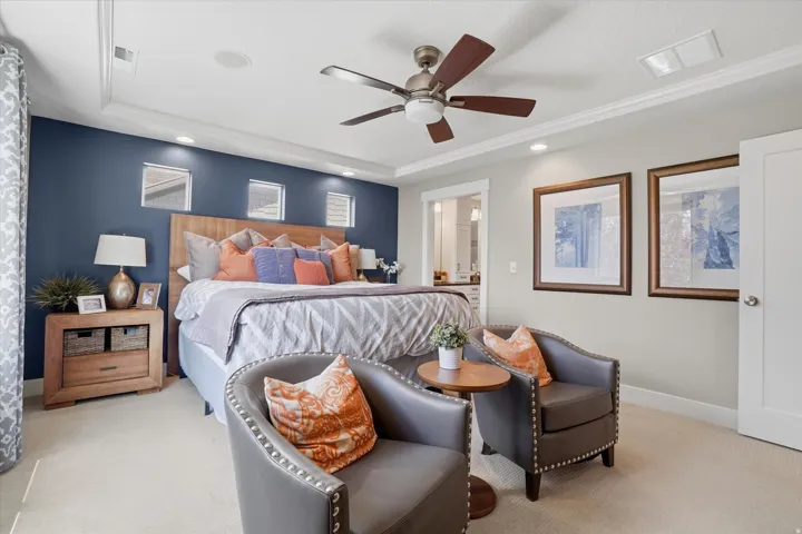 Bedroom featuring a tray ceiling with recessed lighting and a ceiling fan, a prominent accent wall, and light-toned carpeting