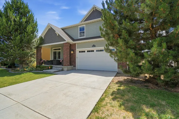 Two-story residence featuring brick and siding facade, covered front porch, attached garage, and a concrete driveway