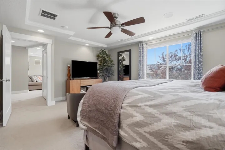 Expansive room featuring a large window, tray ceiling with recessed lighting, ceiling fan, and carpeted flooring