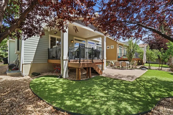 Expansive outdoor living area featuring a covered deck, wood decking, black metal railings, and a concrete patio
