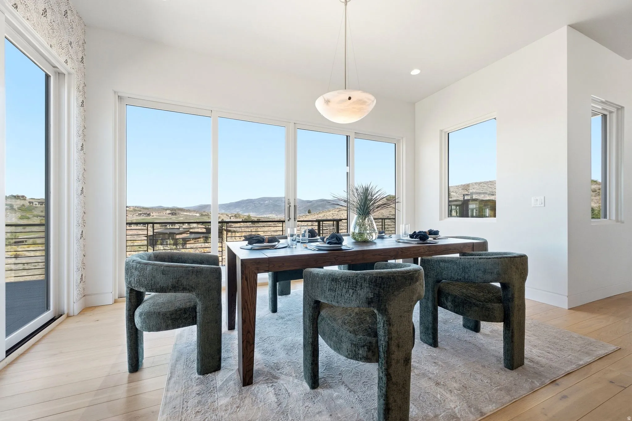 Expansive sliding glass doors, multiple large windows, recessed ceiling lighting, and a modern pendant light fixture