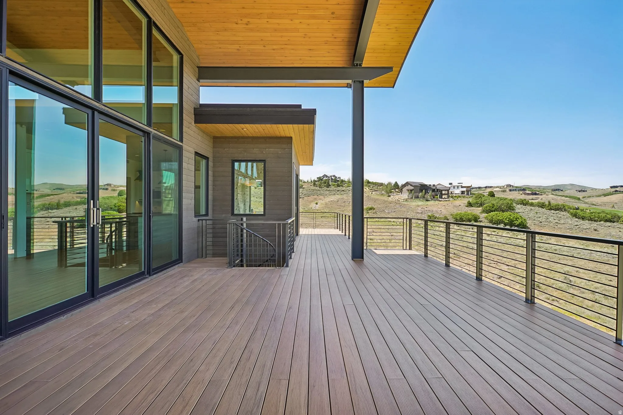 Expansive exterior deck featuring composite decking, cable railing, and a wood-paneled ceiling