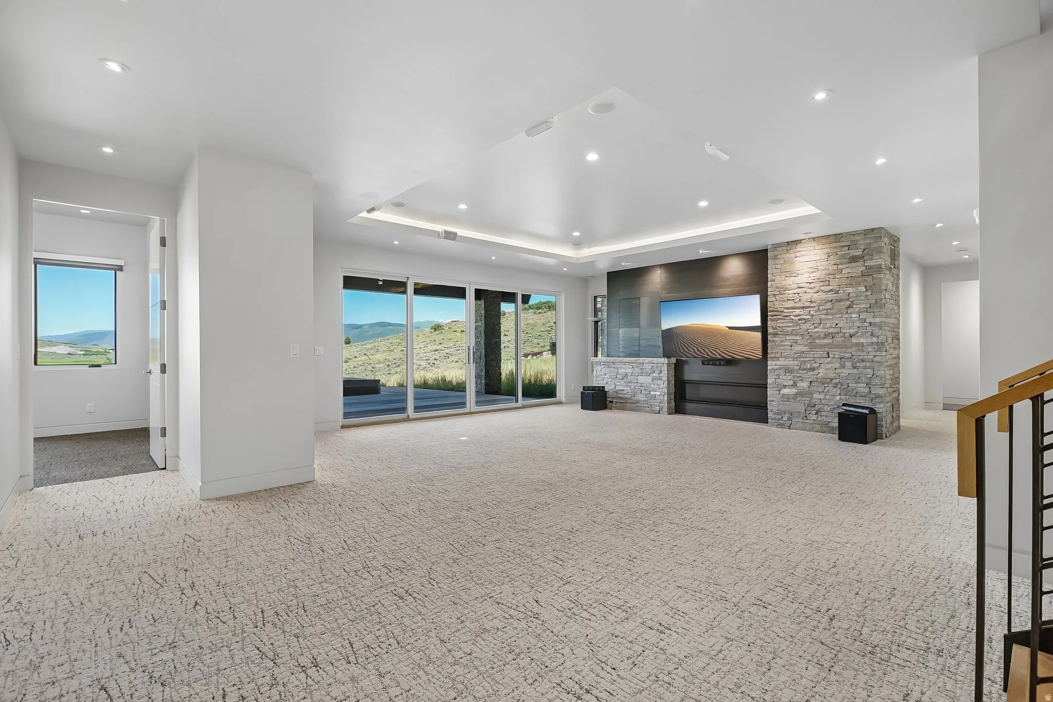 Spacious entertainment area featuring a stone accent wall, recessed lighting, and large sliding glass doors