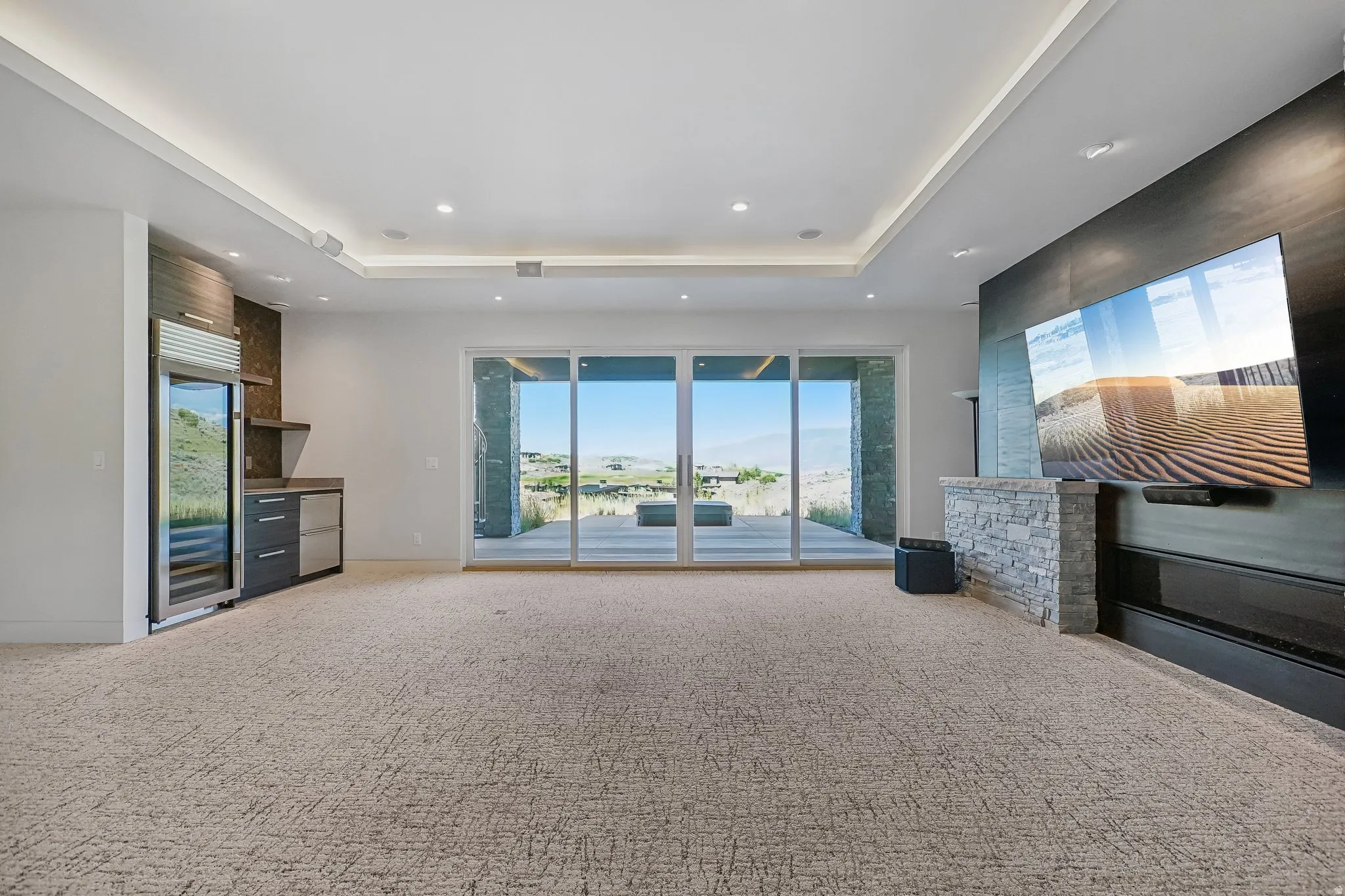 Expansive room featuring sliding glass doors to the exterior, recessed lighting, and tray ceiling